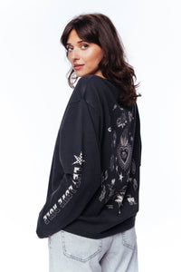 Woman wearing a black sweatshirt with white graphics on a white background