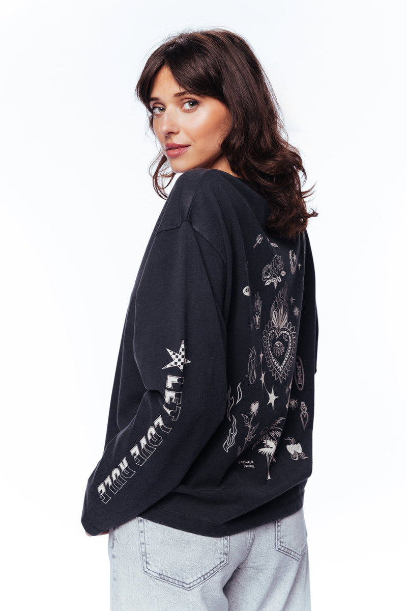 Woman wearing a black sweatshirt with white graphics on a white background